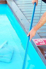 Hand of caucasian pool cleaner during his work. Cleaning robot for cleaning the botton of swimming pools. Automatic pool cleaners.   