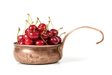 rustic copper ladle with sweet cherry isolate on white