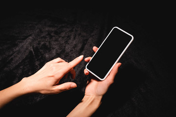 cropped view of woman holding smartphone with blank screen on black velvet cloth
