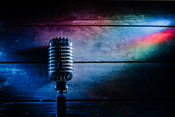 Retro microphone on wooden background and color lights with copy space for text. Horizontal