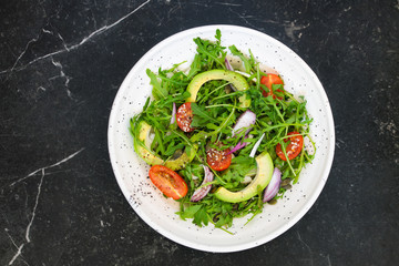 Vegan food. Healthy salad of fresh vegetables - tomatoes, avocado, arugula, onion and seeds on a bowl. Diet menu.  