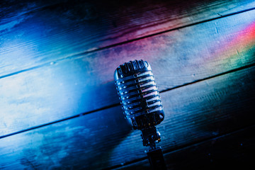 Retro microphone on wooden background and color lights with copy space for text