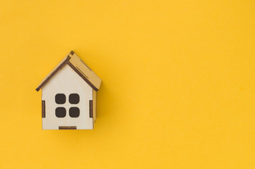 the concept of renting real estate, house toy on a yellow background view from above, of the IOC up and save space