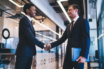 Sprightly multiethnic men entrepreneurs making agreement at office