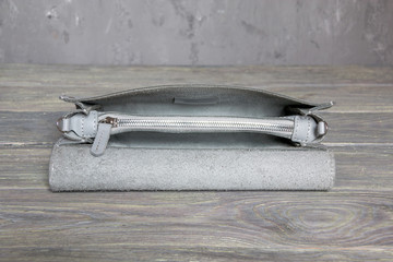 Close up, open and empty leather elegant women handbag on grey background. Horizontal orientation