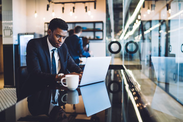 Busy African American man executive browsing laptop at office cafe