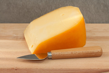 Piece of cheese on a wooden board.