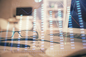 Financial chart hologram with glasses on the table background. Concept of business. Double exposure.