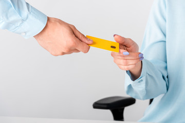 cropped view of man giving yellow credit card template to woman isolated on white