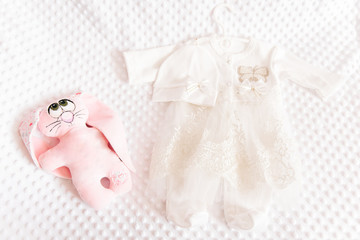Cute baby dress on light background for christening girl and toy nearby