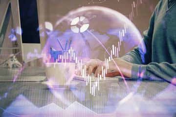 Multi exposure of graph with man typing on computer in office on background. Concept of hard work.