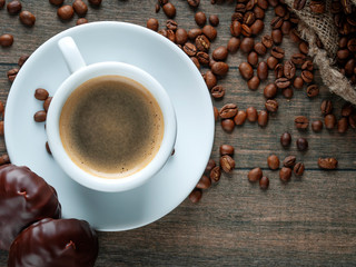 Cup of coffee and coffee beans with oatmeal cookies for breakfast on a wooden background. Photo for...