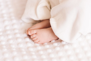 Fototapeta na wymiar Close up of tiny adorable bare pink baby feet as the infant sleeps on white blanket
