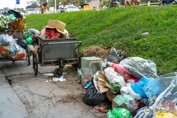 Pile of garbage bags and messy trash on street sidewalk with traffic on background in Hanoi, Vietnam