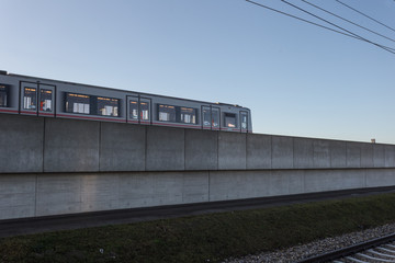 Metro train passing along concrete barrier on its way to the suburbs