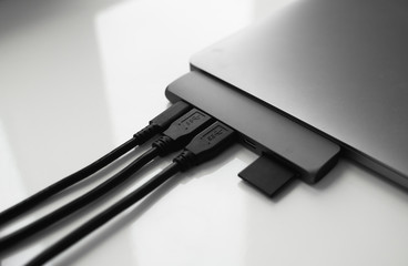 Laptop with USB Type-C adapter with pluged USB cables and SD card. The USB adapter under the Type-C...