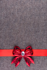 Vertical image with red bow on red ribbon on gray