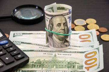 Fototapeta premium dollars, coins and calculator on a black, wooden background. Business concept.