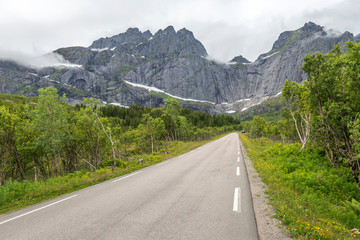Fototapeta premium road and steep rock crags, near Stor lake , Lofoten, Norway