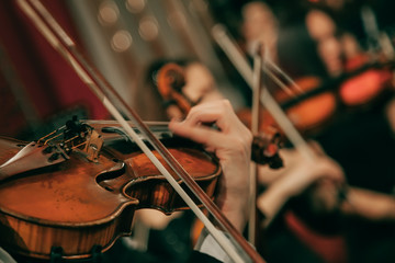 Symphony orchestra on stage, hands playing violin. Shallow depth of field, vintage style. - obrazy, fototapety, plakaty