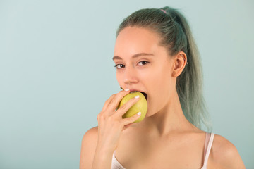 beautiful slender young woman in sportswear bites an apple