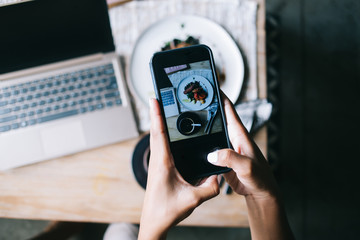 Lady taking photo of meal using mobile phone
