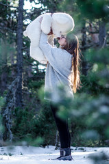 Blonde girl lifts the teddy bear high giving it a sweet kiss in the middle of the forest. Sunlight reflects in your hair, concept of happiness, gift.