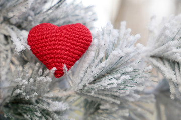 Christmas heart, red knitted symbol of love in the snow on fir branches. Background for romantic card, New Year celebration, Valentine's day or winter weather