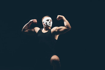 Athlete bodybuilder on a dark background. Dramatic portrait. The masked man.