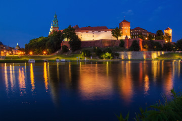 Fototapeta na wymiar Illuminated Wawel Royal Castle in the evening. Beautiful reflection in the Wisla river. Krakow, Lesser Poland, Poland.