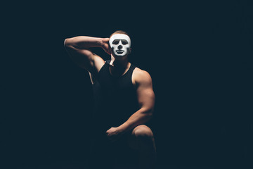 Athlete bodybuilder on a dark background. Dramatic portrait. The masked man.