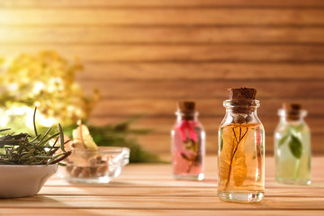 Jars with plant and essence inside on table wooden background - obrazy, fototapety, plakaty