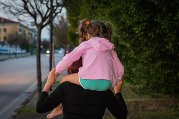 grandmother is carrying her granddaughter on her shoulders