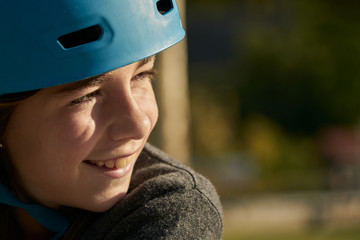 Smiling girl with blue safety bicycle helmet and background of urban landscape and nature