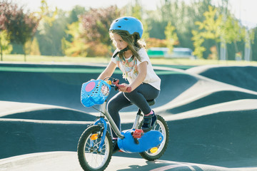 The bike lane for children. Children have fun on the race pump track. A child in a blue helmet riding a bicycle for safety