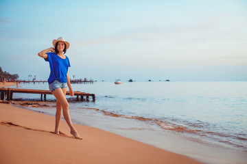 Young woman in hat standing on sand and dreaming.