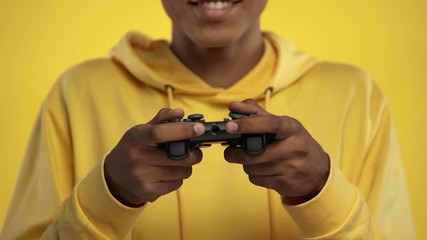 KYIV, UKRAINE - OCTOBER 18, 2019: cropped view of african american teenager playing video game isolated on yellow