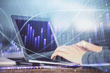 Double exposure of businessman's hands with laptop and stock market graph background. Concept of...