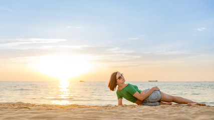 Fototapeta na wymiar Caucasian woman relaxing at seashore. Sunset on the background.