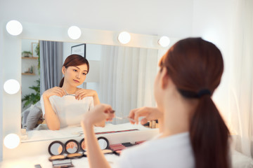 Obraz na płótnie Canvas A beautiful Asian girl holding an eyelash curler in her hand as a makeup accessory.