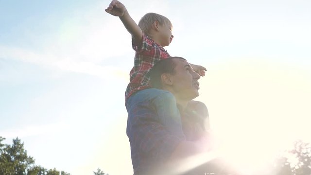 Happy Family Father Son Concept. Father Giving Son Ride On Back In Nature Outdoors . Portrait Of Happy Father Giving Son Ride On Lifestyle His Shoulders And Looking Up. Cute Boy With A Dad Playing