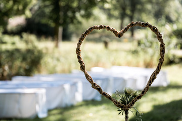 Geflochtenenes Herz aus Holz vor unscharfen B&auml;nken in wei&szlig;