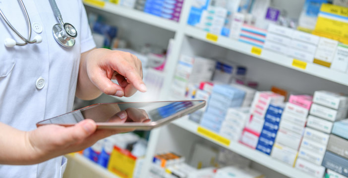 Doctor using computer tablet for search bar on display in pharmacy drugstore shelves background.Online medical concept.