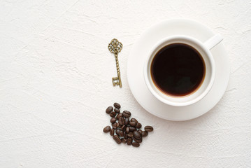 Hot cup of coffee and coffee beans on white table flat lay background.