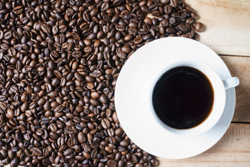 Top View of Coffee cup and roasted coffee beans on a wooden table