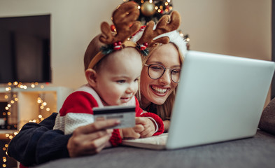 Woman and baby online shopping. Close up of a young woman and her baby buying presents online.