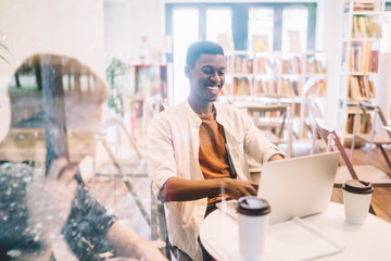 Fototapeta premium Cheerful millennial generation Z with toothy smile on face enjoying online network communication on modern laptop computer, happy successful male laughing while watching funny social video vlog