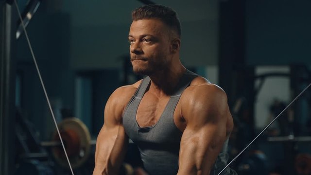 Muscular bodybuilder at cable crossovers fitness men pumping up muscles. Workout fitness exercises and bodybuilding concept background - Handsome athletic men doing bars exercises in gym naked torso