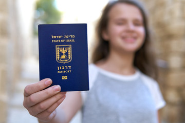 Happy teenage girl showing the passport of the State of Israel holding it in hand