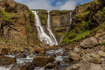 Obraz premium View of a triple waterfall with cascades of a mountain river in the foreground